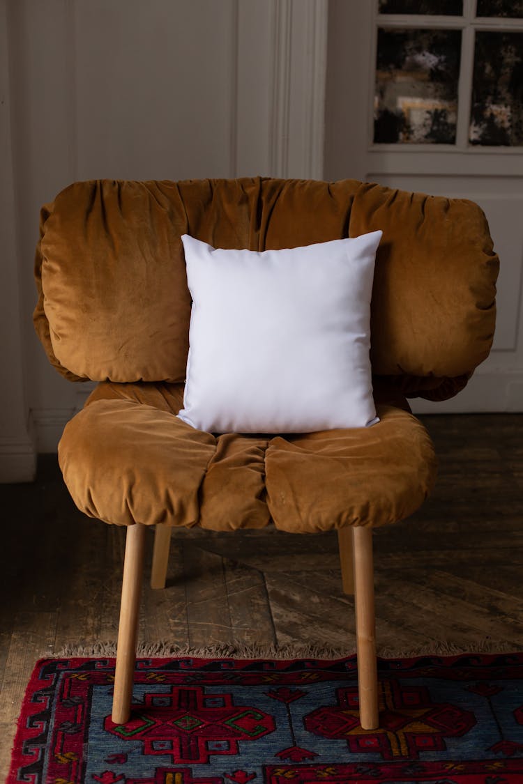 Brown Chair With A White Throw Pillow