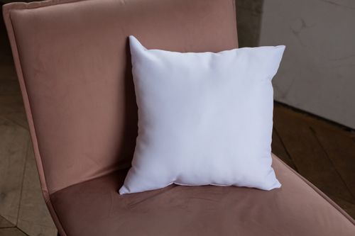 Free A simple white pillow rests on a beige chair, highlighting minimalist decor. Stock Photo