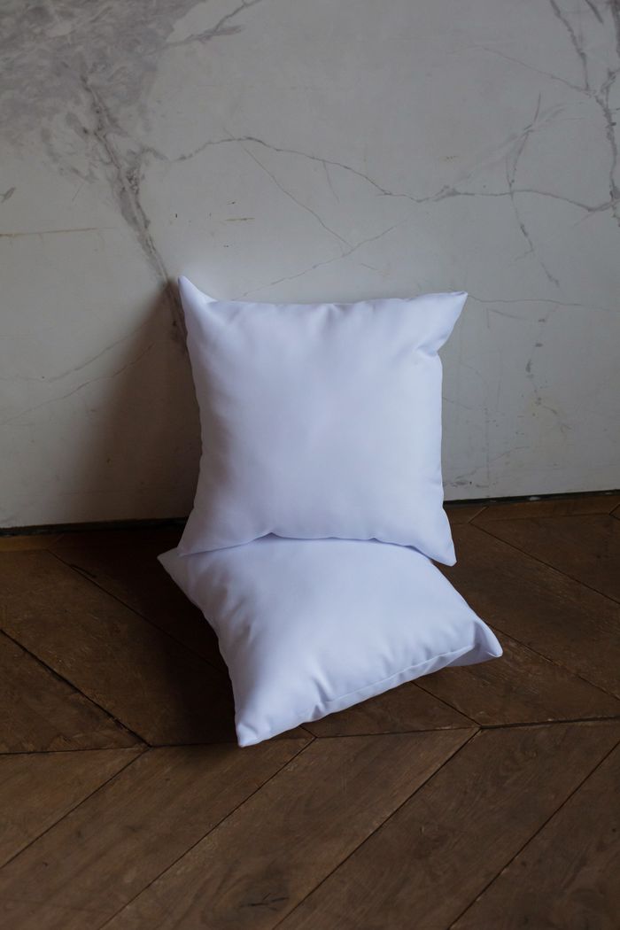 Two white seat cushions leaning against a pale wall, photo by KATRIN BOLOVTSOVA on Pexels