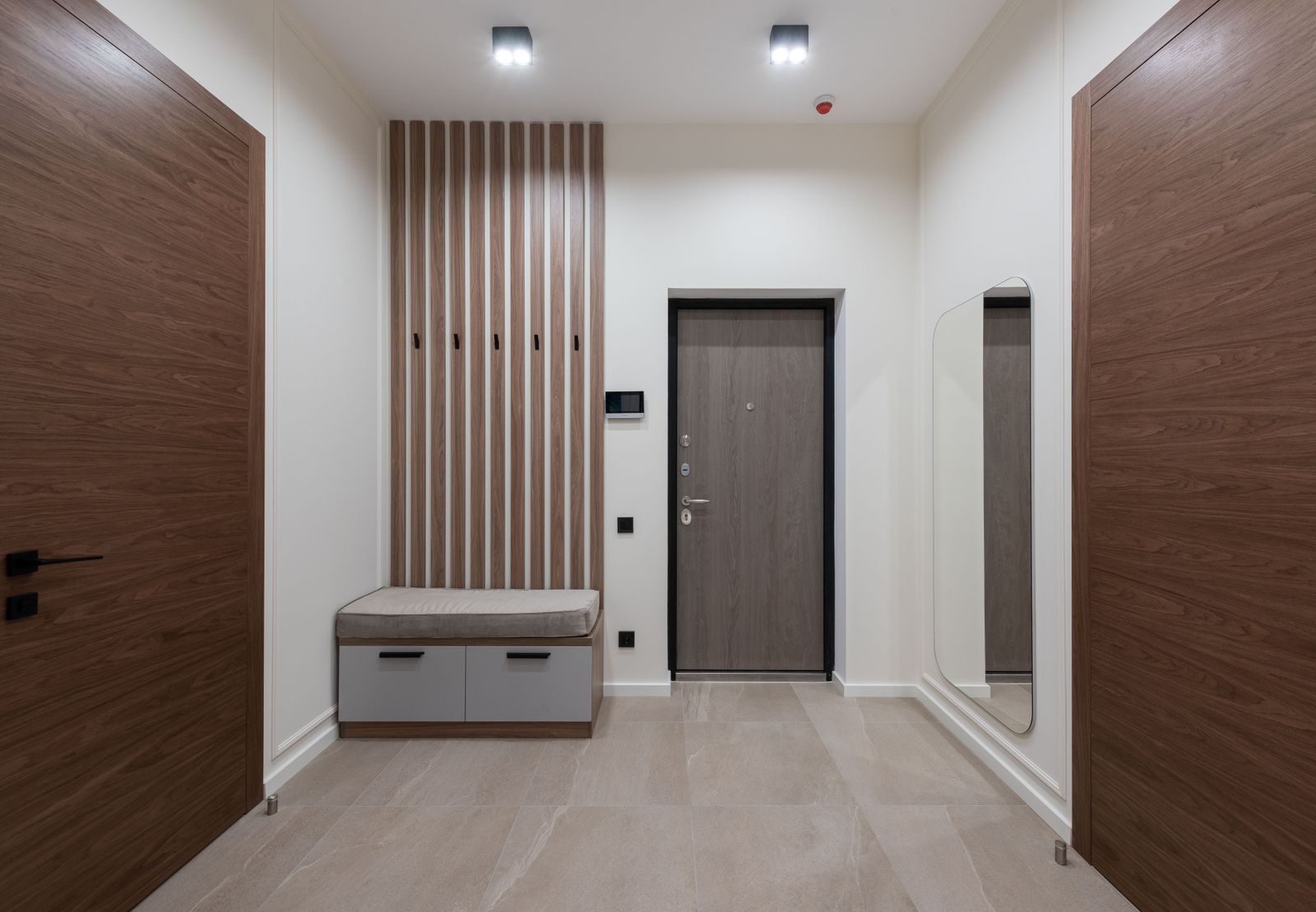 Hall d'immeuble récent, tapis-grattant en cours d'aspiration, sol en béton ciré humide de pluie