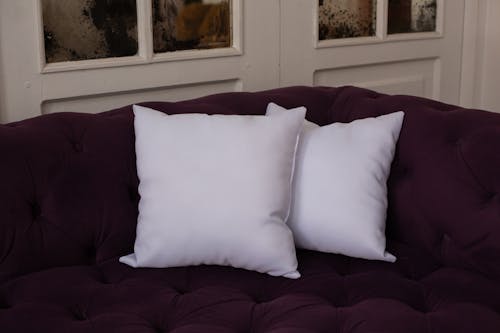 Close-Up Shot of White Pillows on a Purple Sofa