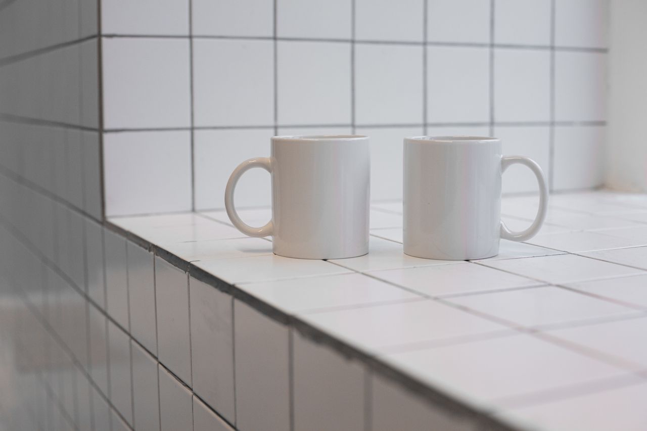 two white ceramic mugs placed on a clean tiled surface perfect for min