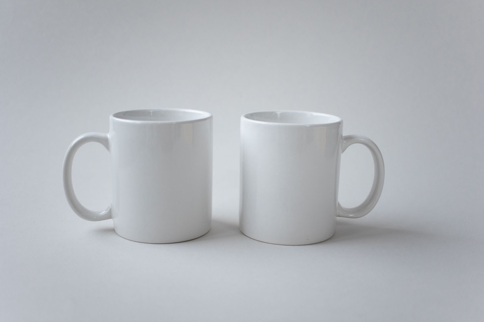 Two white ceramic mugs displayed against a simple white background, showcasing minimalist design.