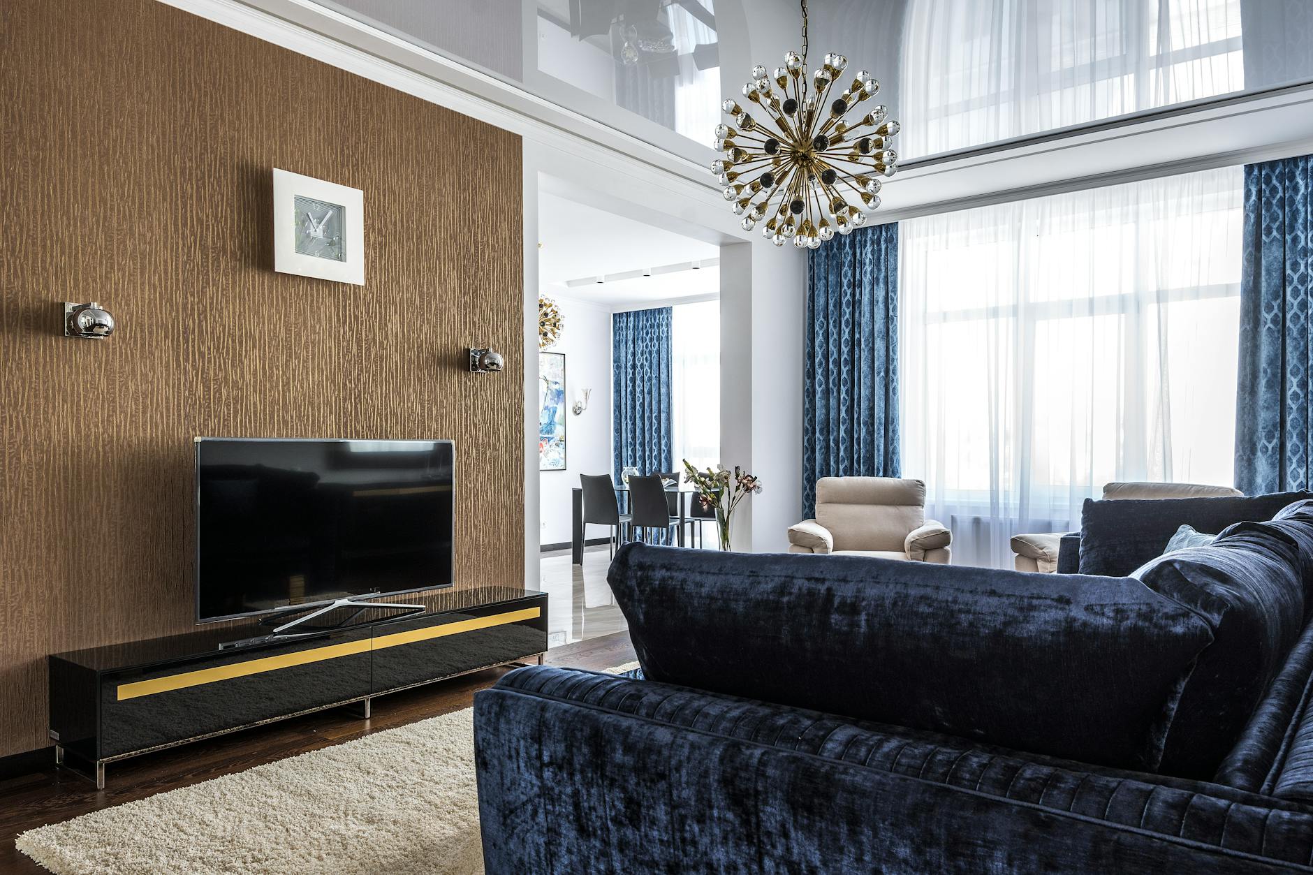 Interior design of spacious living room with comfortable couch with armchairs and TV set in modern apartment