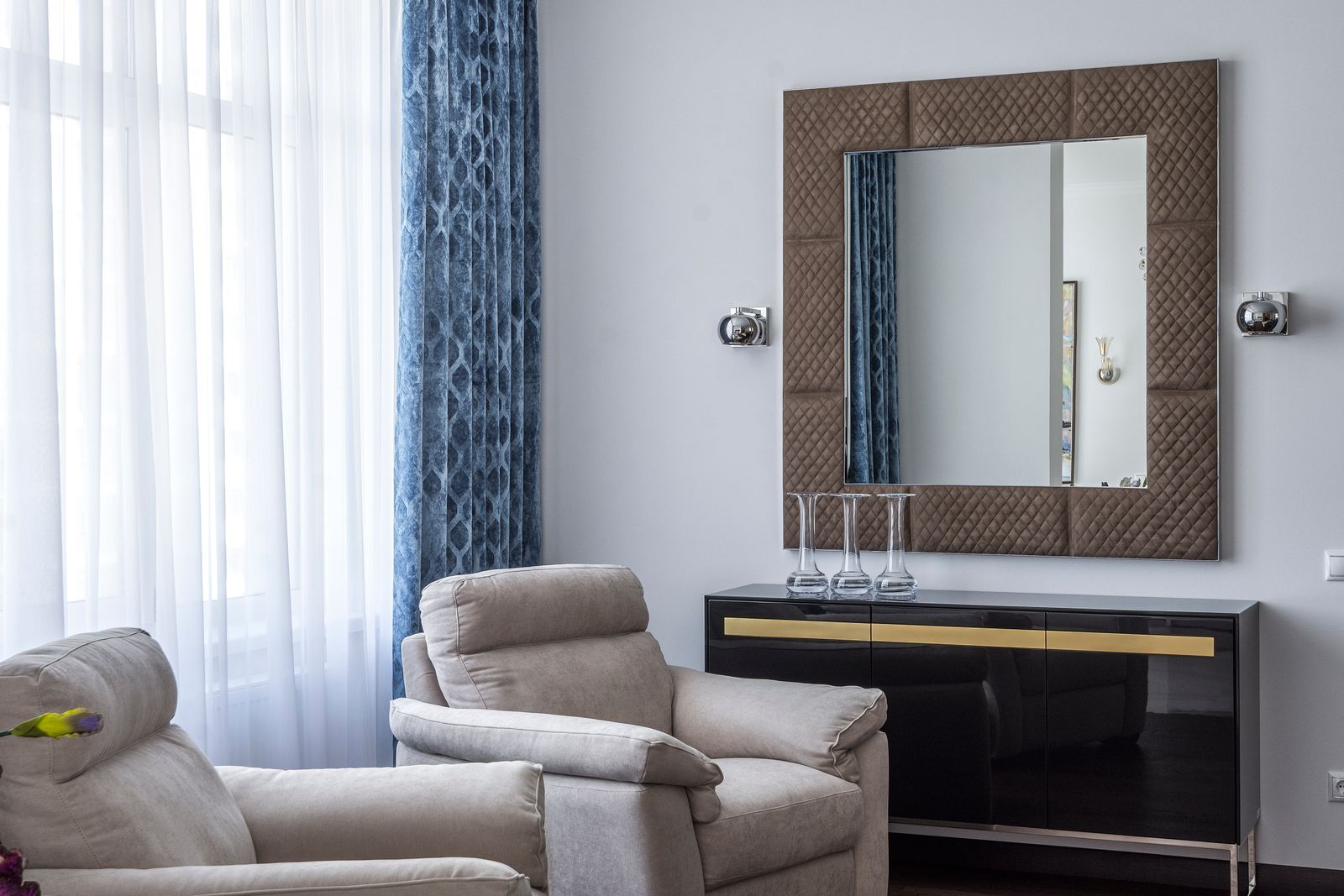 Sala contemporânea com poltrona e espelho quadrado na composição.