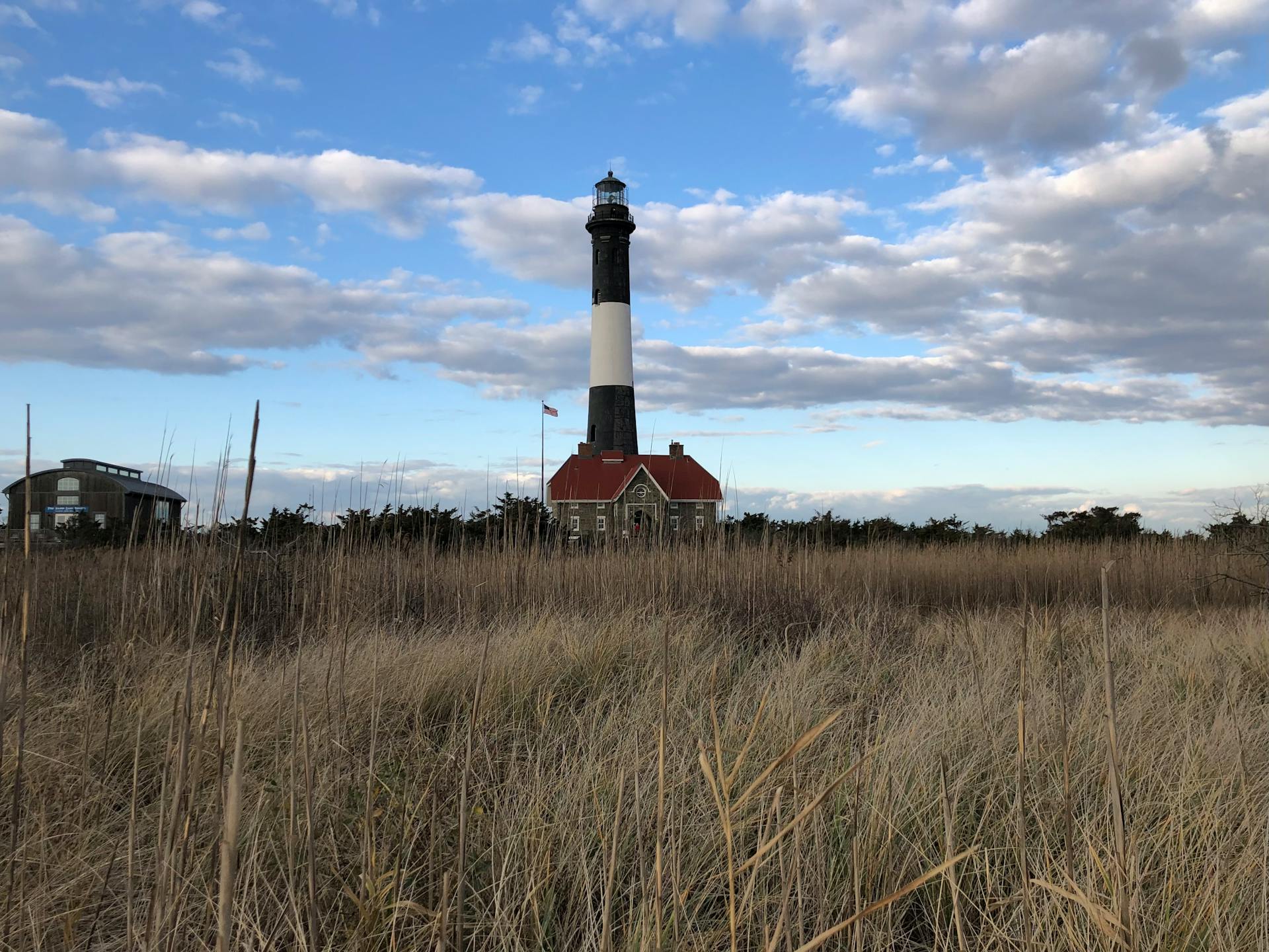 Beautiful view of Fire Island Lighthouse with a golden sky and field. Iconic New York landmark.