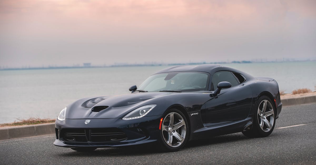 Luxurious black sports car parked on a coastal road under a serene sky.