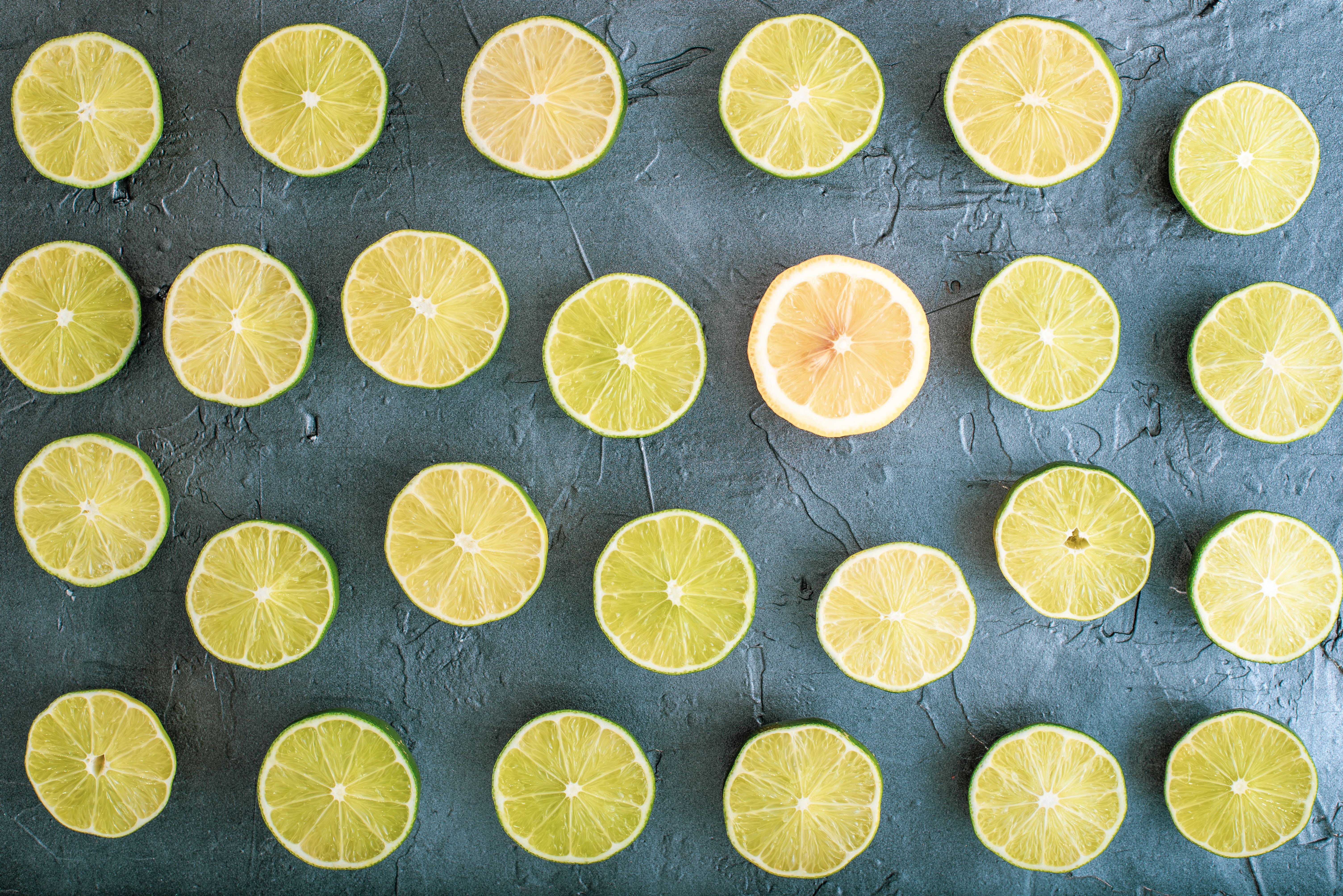 Top view of lime and lemon slices arranged in a pattern on a textured gray background.