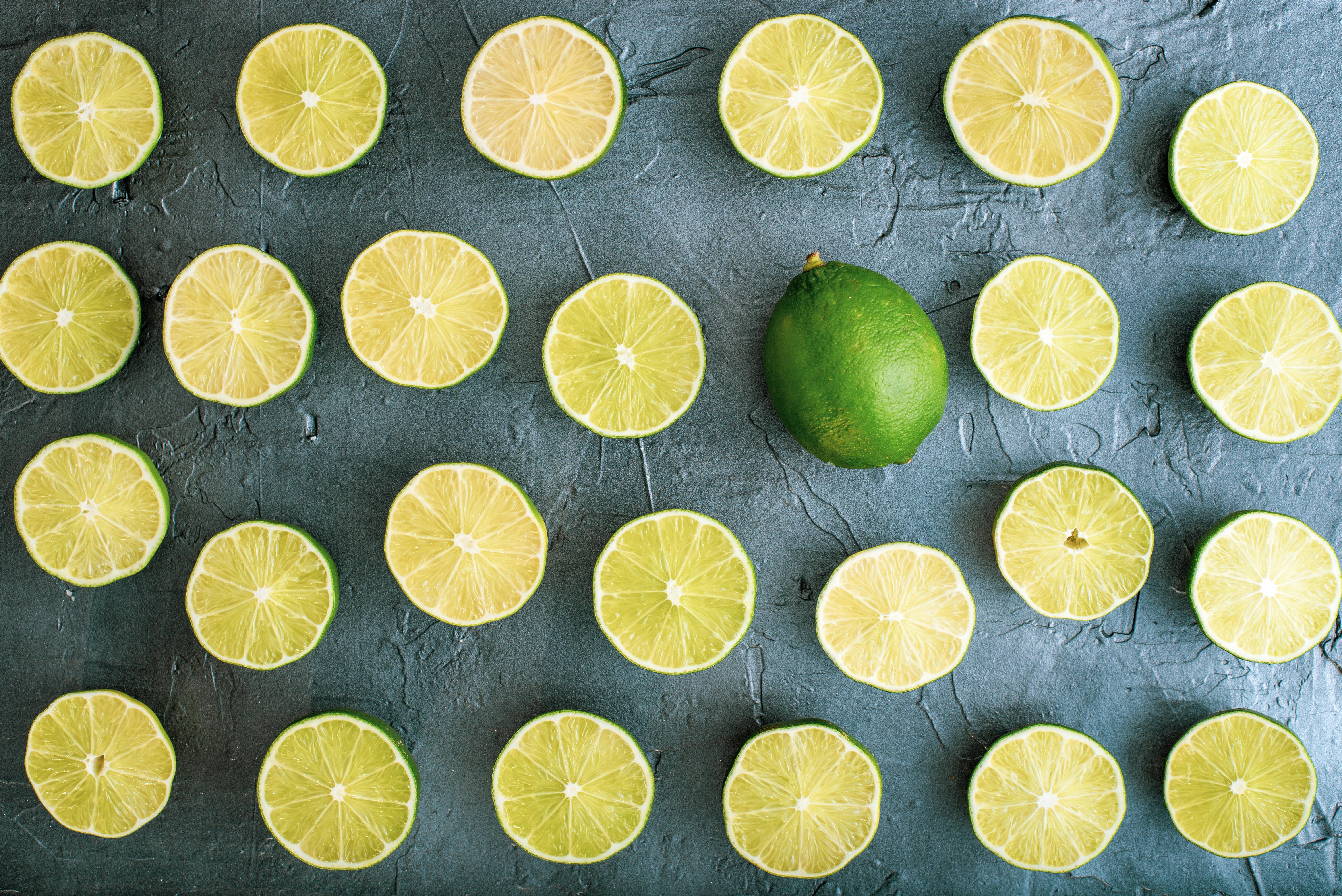 Top view of lime slices arranged on a gray textured background.