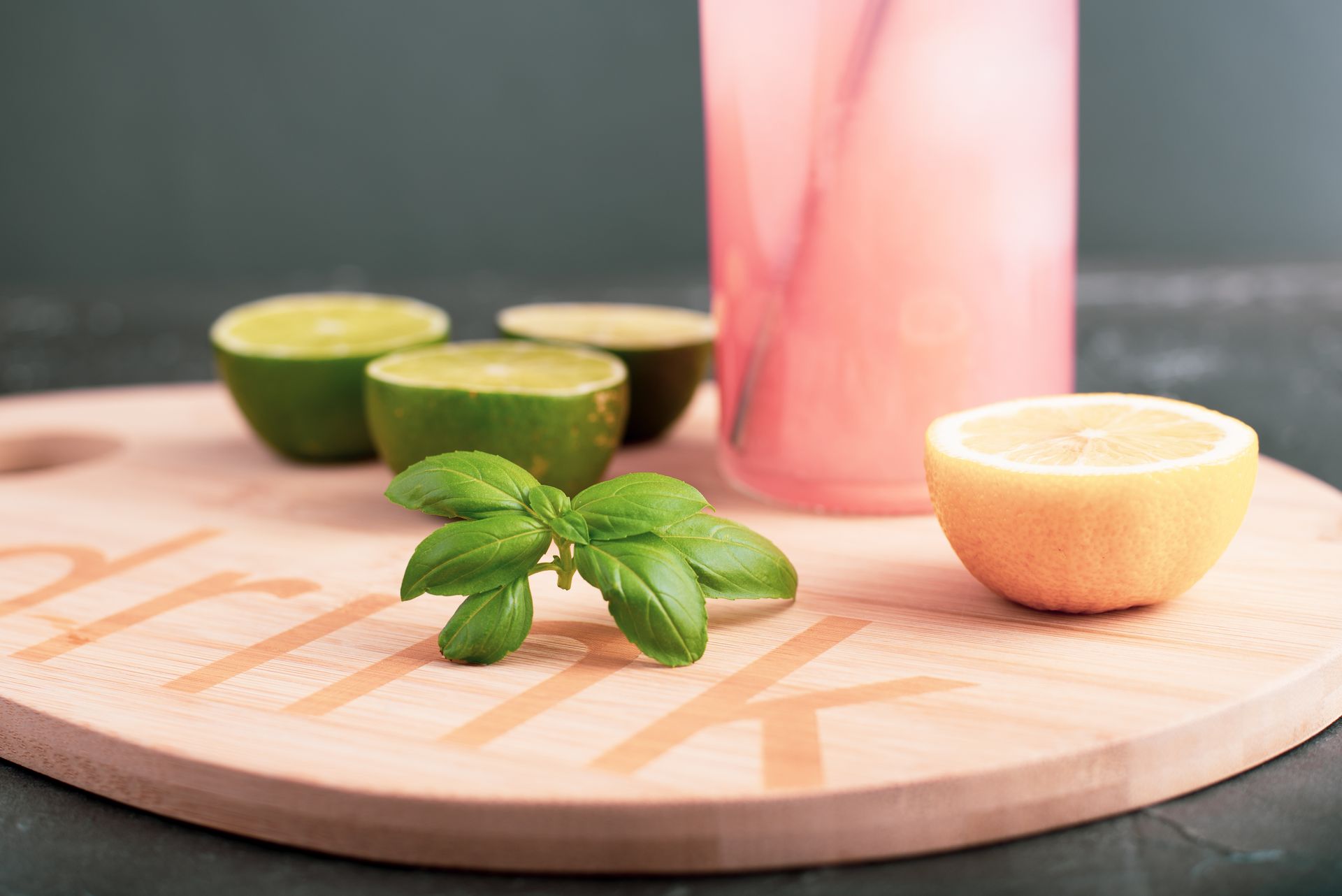 Close-up of a refreshing drink with citrus fruits and basil on a wooden platter.