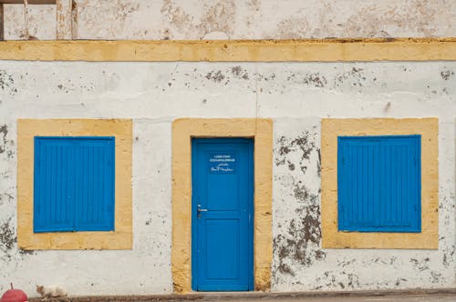 Old shabby building facade with blue door and windows