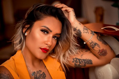Free Alluring young woman with piercing and tattoos on curvy body looking at camera with hand on head Stock Photo