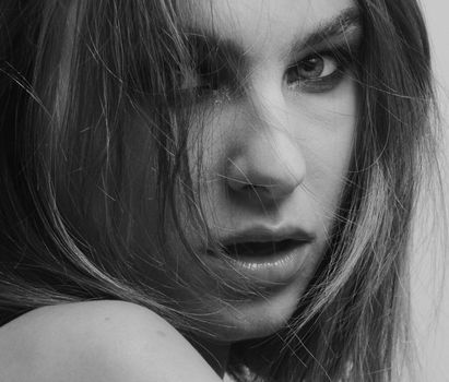 Striking black and white portrait highlighting a woman's intense gaze and messy hair.