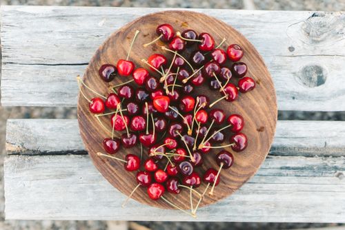 Free Top-view of fresh red cherries on a rustic wooden plate, perfect for food themes. Stock Photo