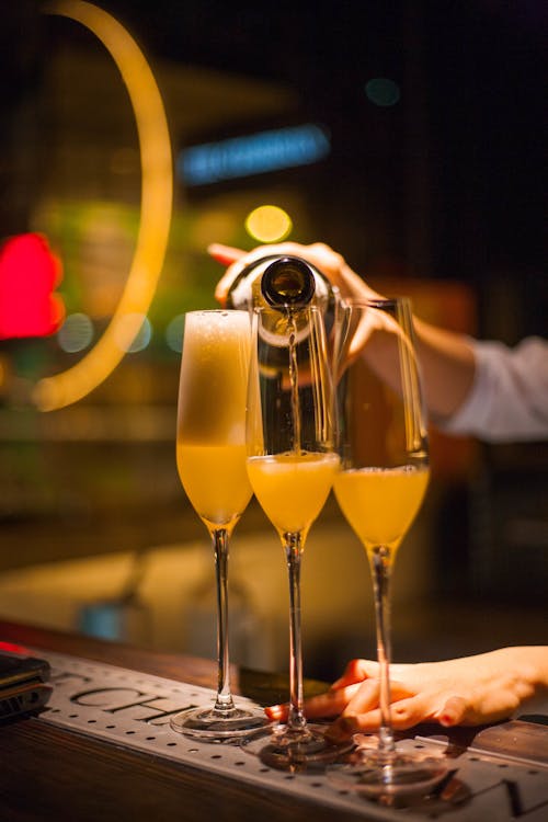 A Person Pouring Champagne into Glasses on a Bar