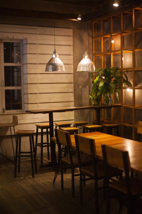 Free Rustic dining area with wooden tables and chairs, warm lighting, and cozy atmosphere. Stock Photo