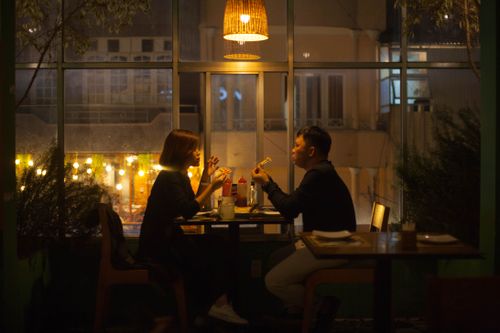 Free A couple enjoys a candlelit dinner in a warm, cozy restaurant interior at night. Stock Photo