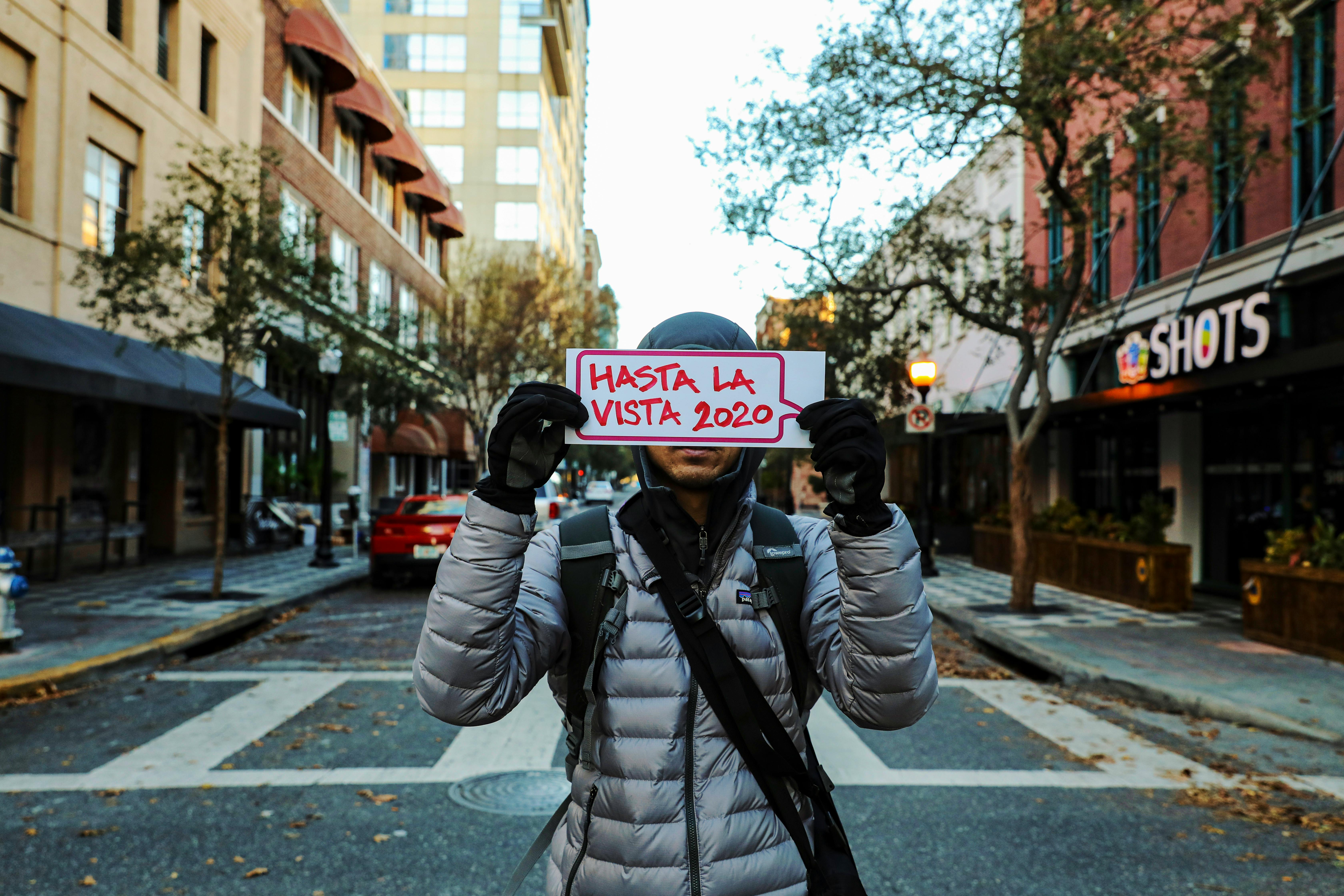 a person in a puffer jacket a holding a placard in the street