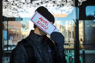 A Person Holding a Placard by a Shop Window