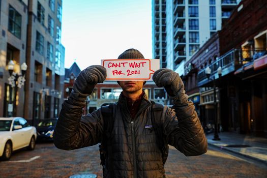 A Person in a Puffer Jacket a Holding a Placard in the Street