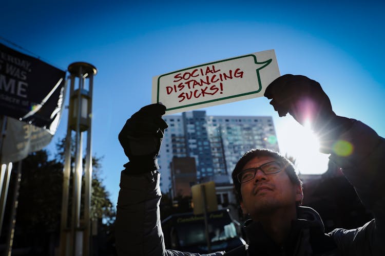 A Man Holding A Placard In The Sun Glare