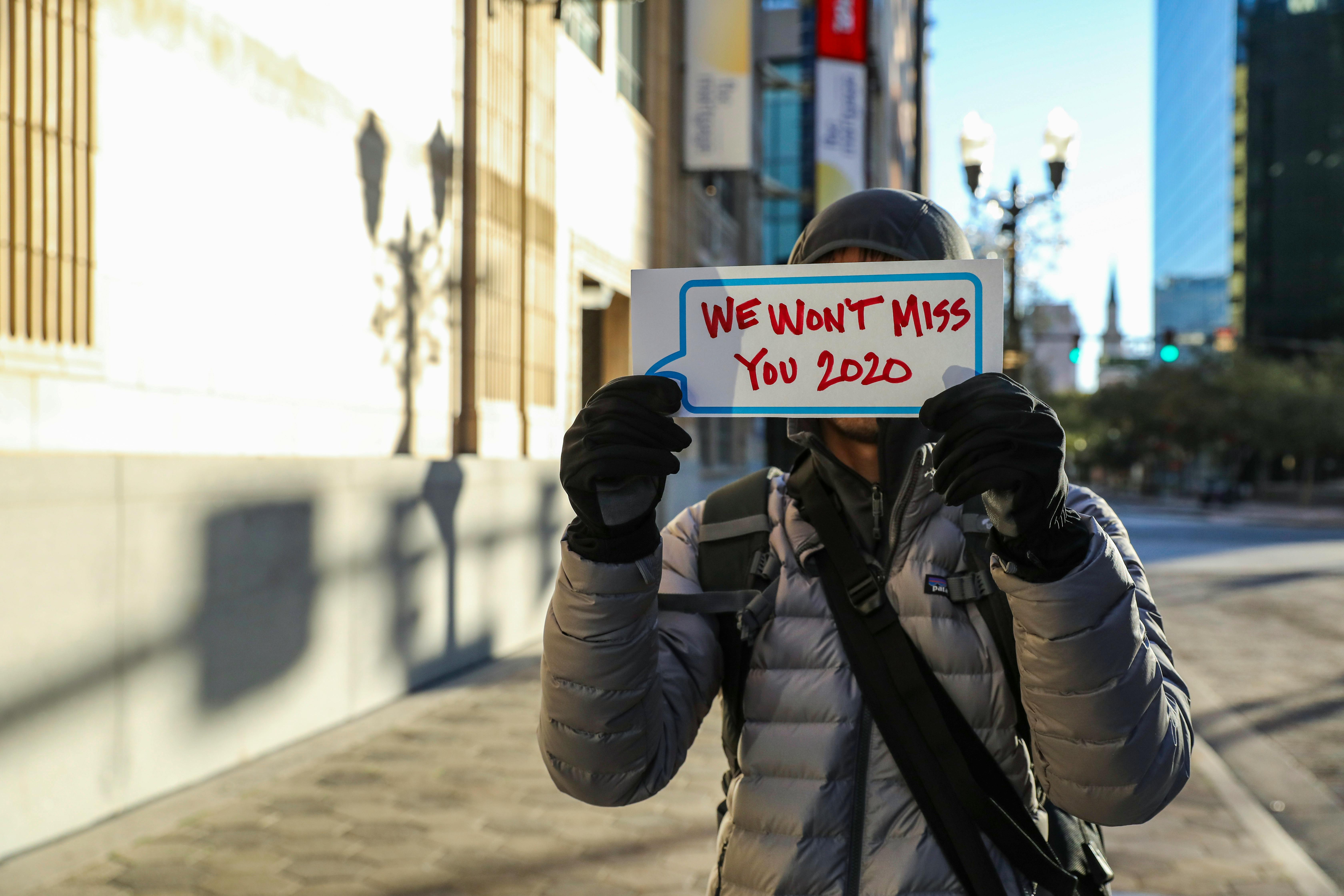 a person in a puffer jacket a holding a placard in the street