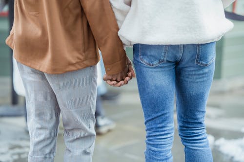 Crop couple holding hands on street