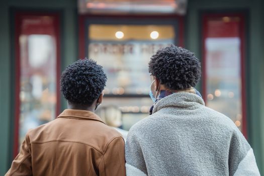 Anonymous black men standing near showcase