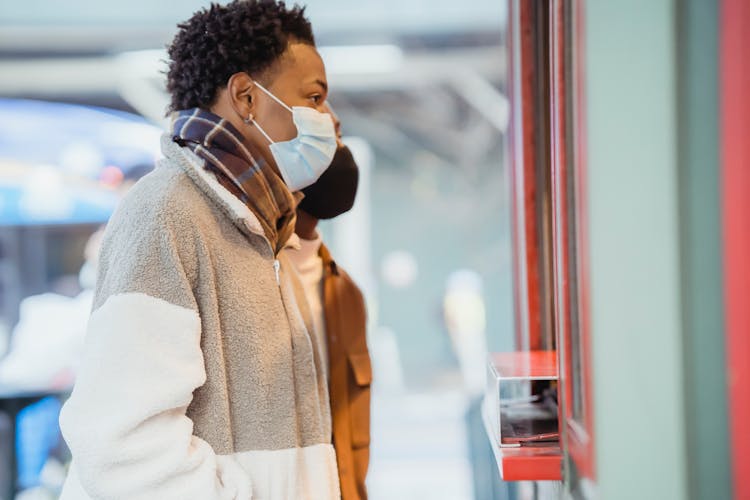 Black Couple In Medical Masks Choosing Goods On Street