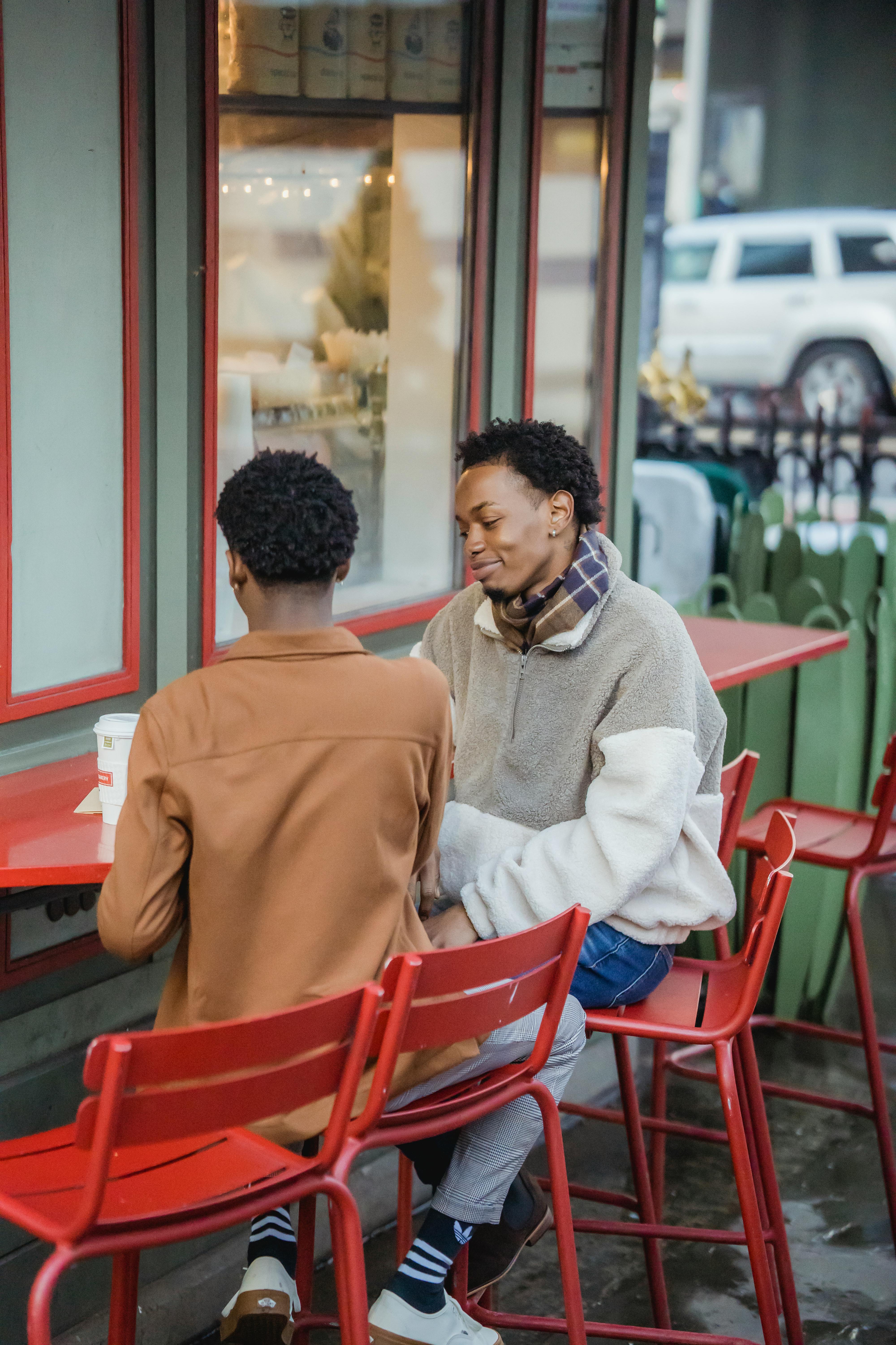 cheerful black men eating on terrace of cafe