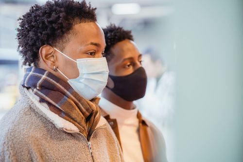 Free Side view of curious African American male couple in protective masks standing together on street in city on blurred background Stock Photo