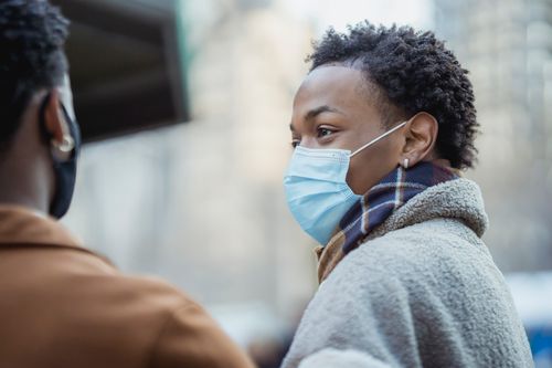 Free African American male wearing protective mask standing near faceless black male partner on street with buildings on blurred background in city Stock Photo