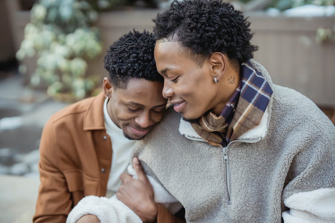 Free Tender African American homosexual male couple cuddling gently while sitting on street in city on blurred background during romantic date Stock Photo