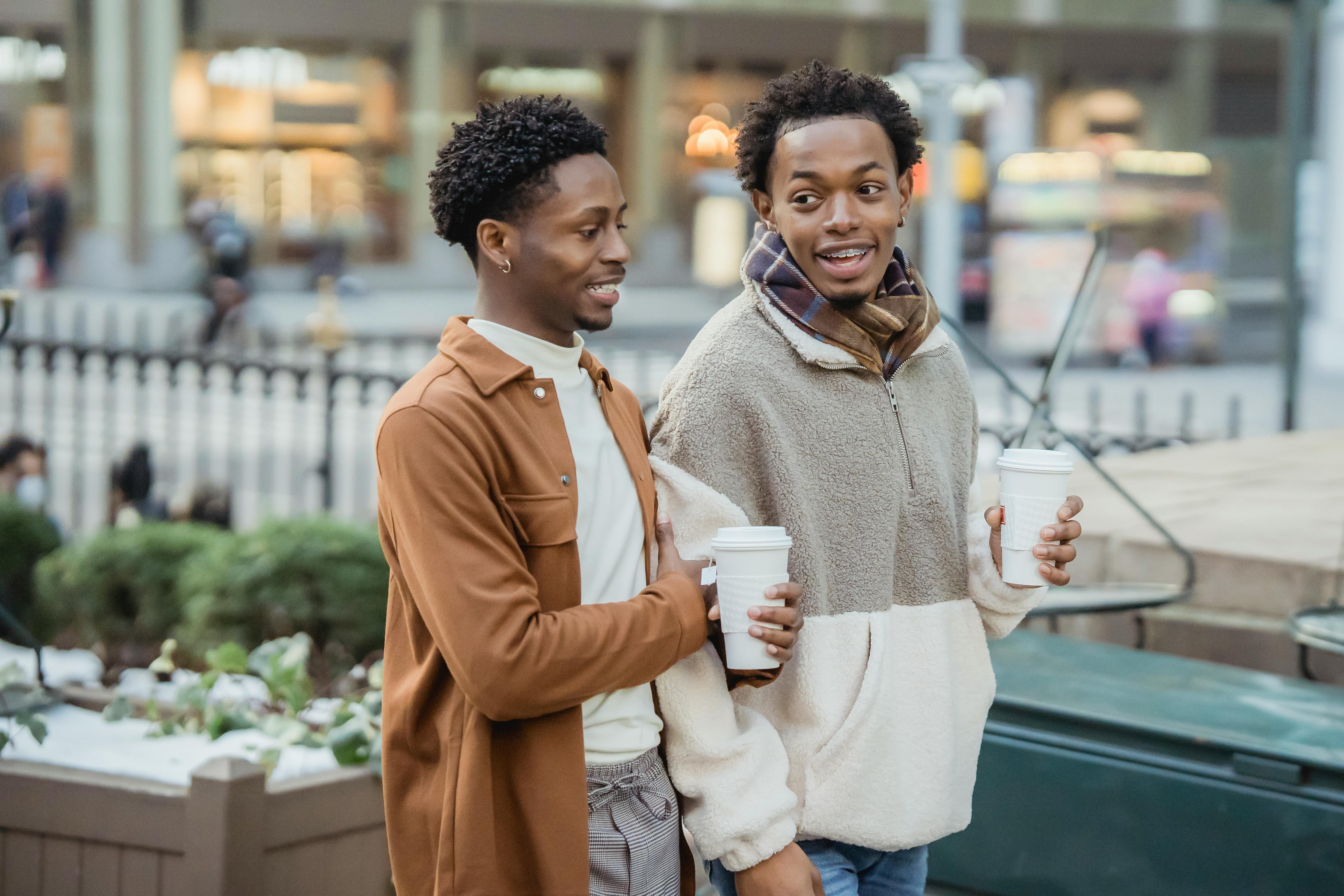 cheerful black homosexual couple chatting while walking on street