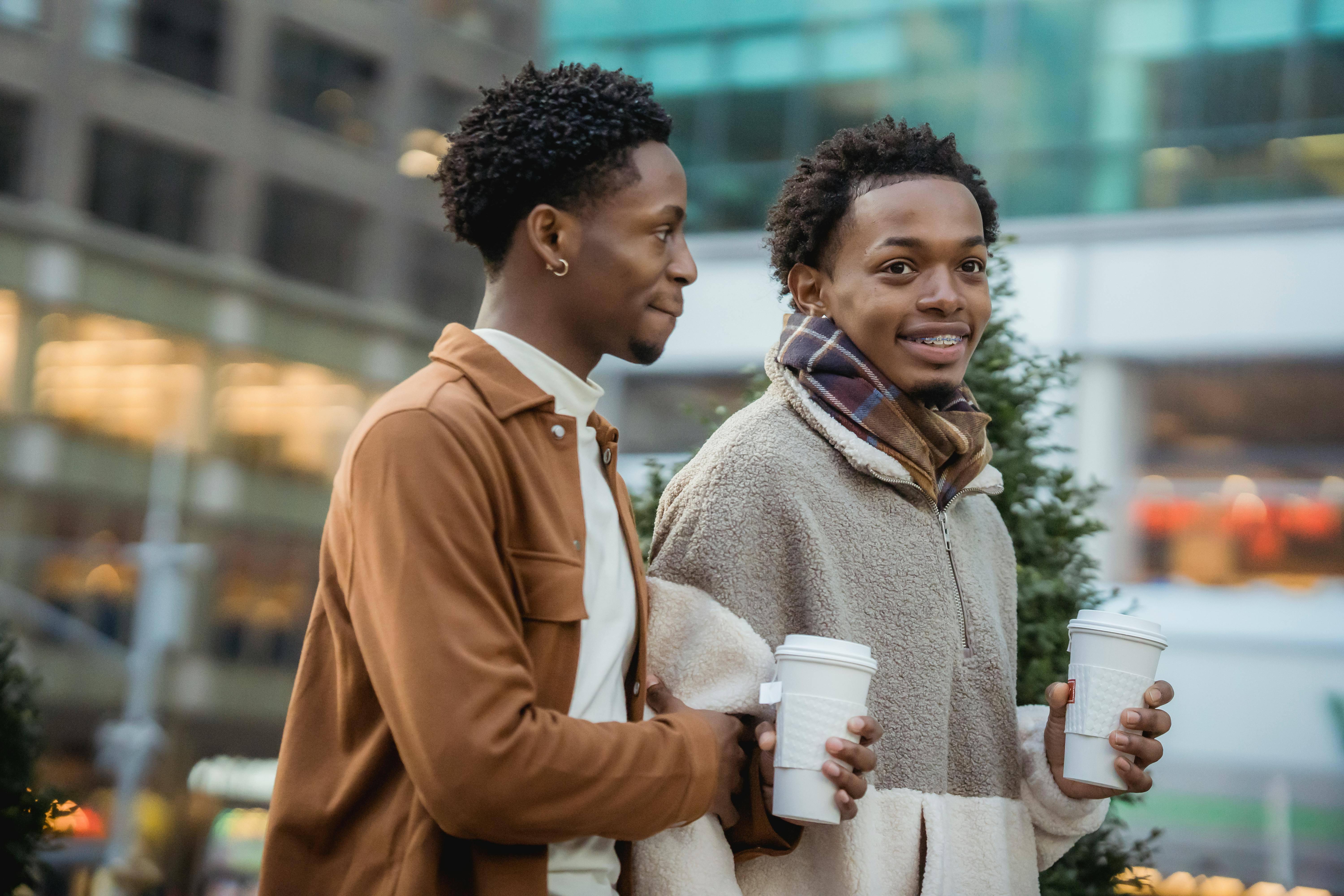 A cheerful couple enjoys coffee while strolling in the city, showcasing love and bonding.