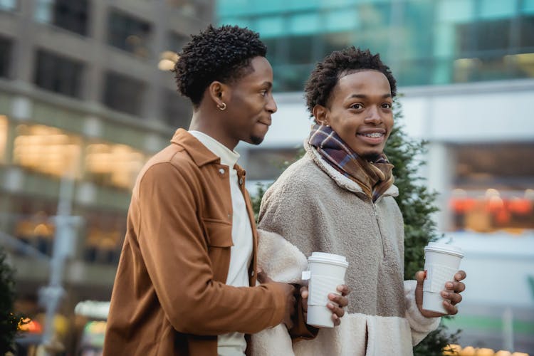 Delighted Black Homosexual Couple With Coffee On Street