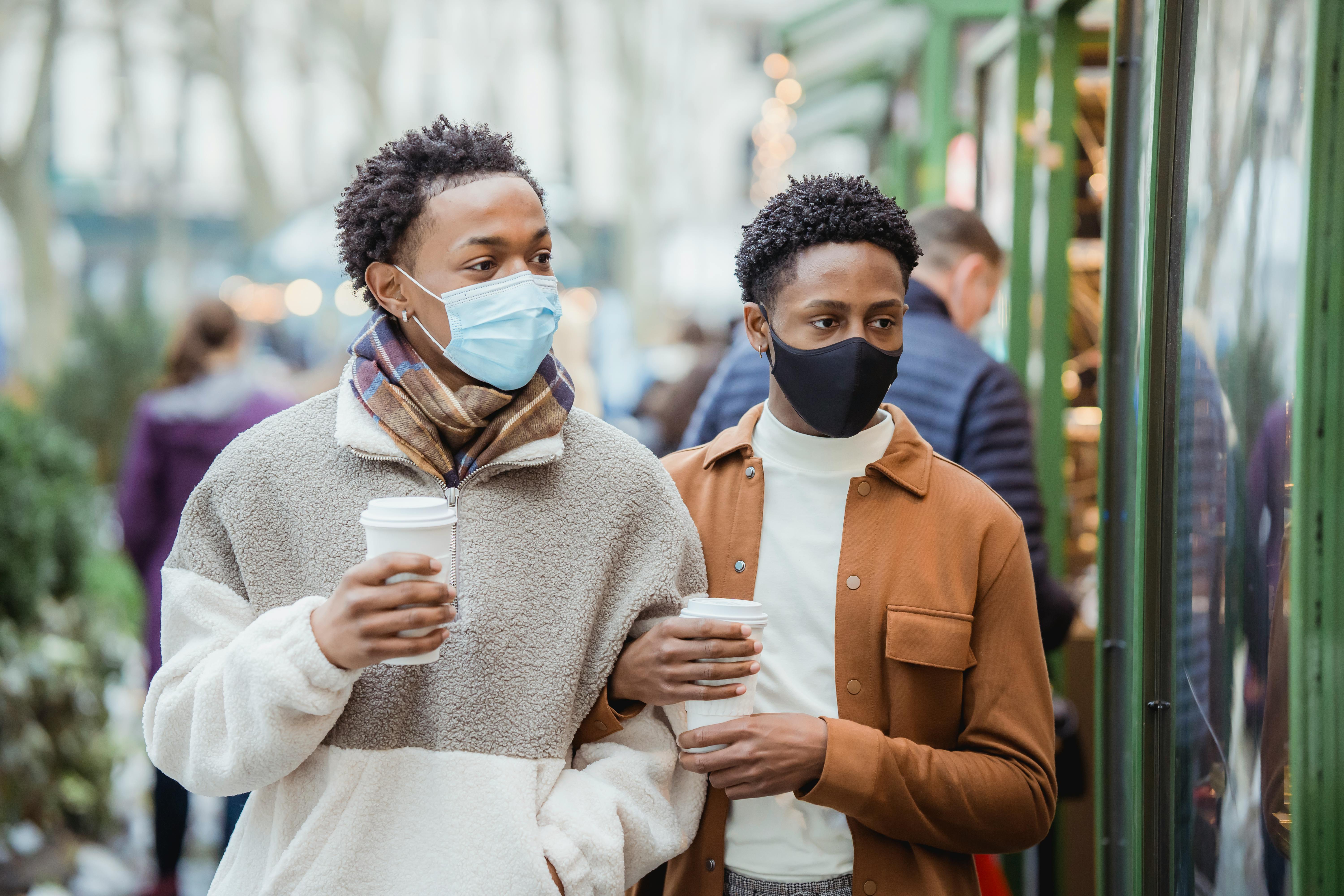 black couple in protective masks looking through glass showcase