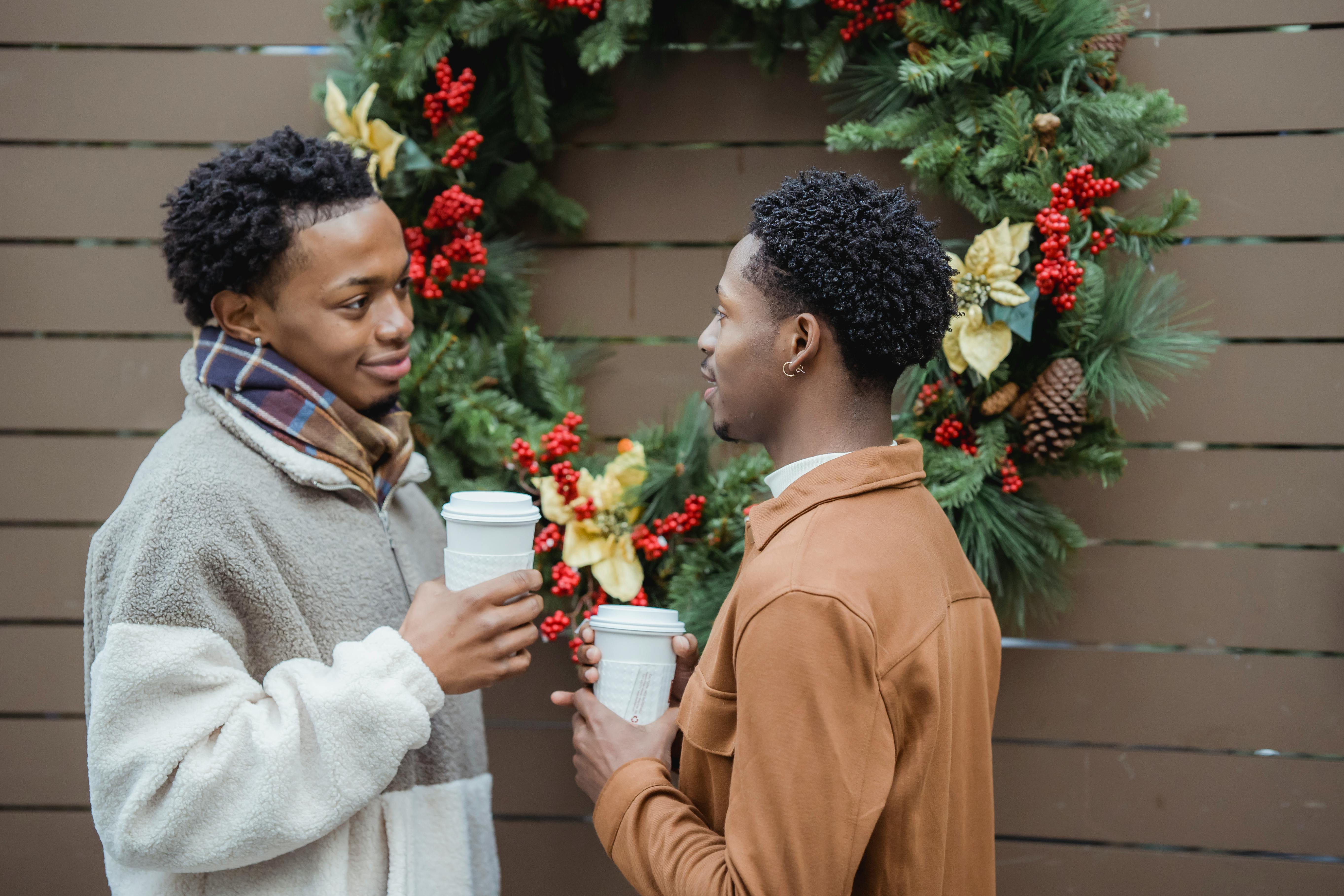 romantic ethnic homosexual men drinking takeaway beverages on street during christmas holidays