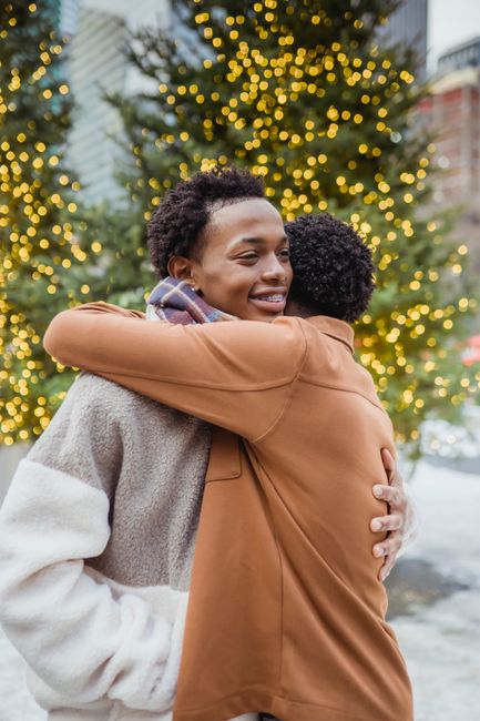 Fotomural Pareja abrazándose al aire libre en un entorno urbano festivo con luces navideñas.