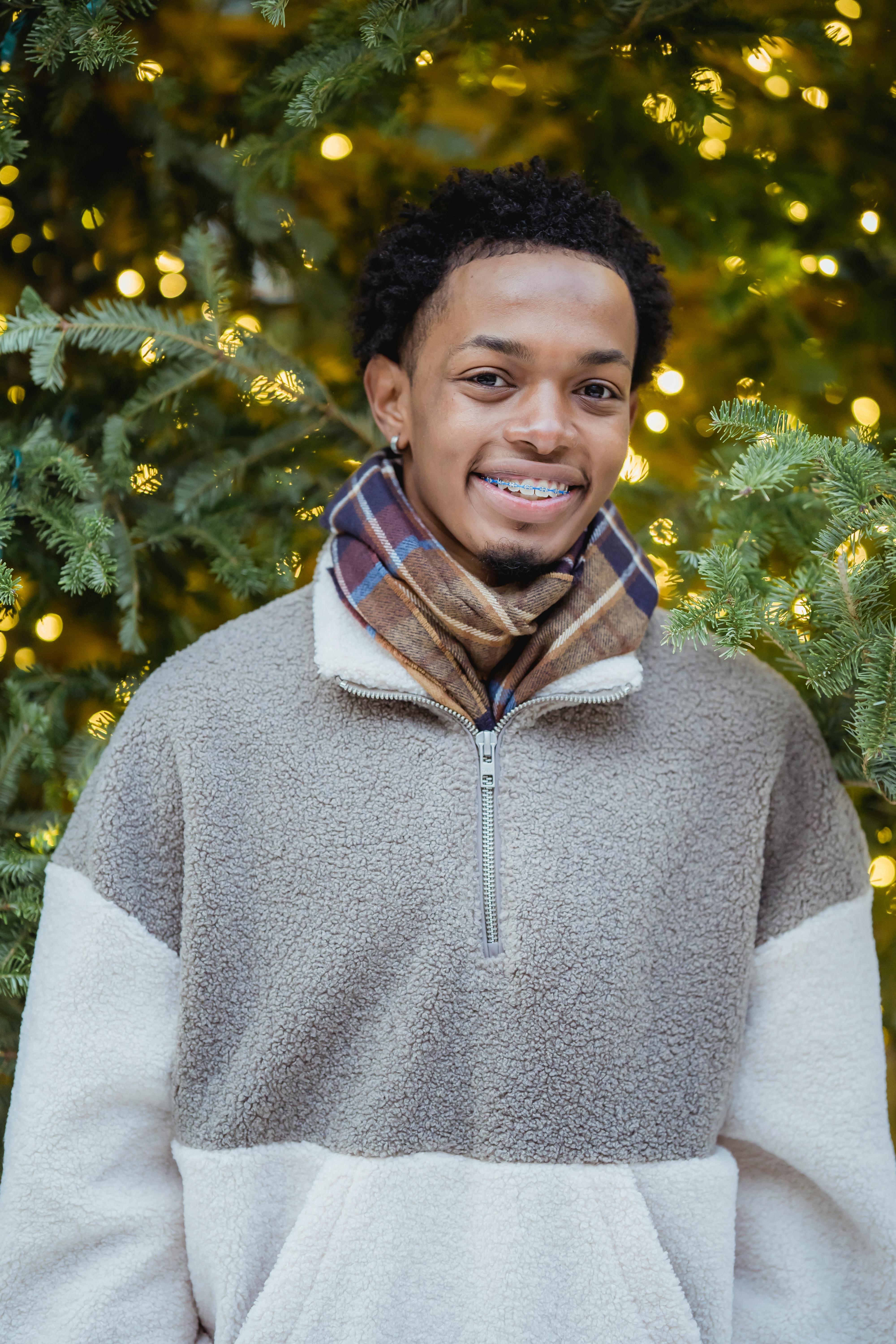 content young african american guy smiling at camera near christmas tree