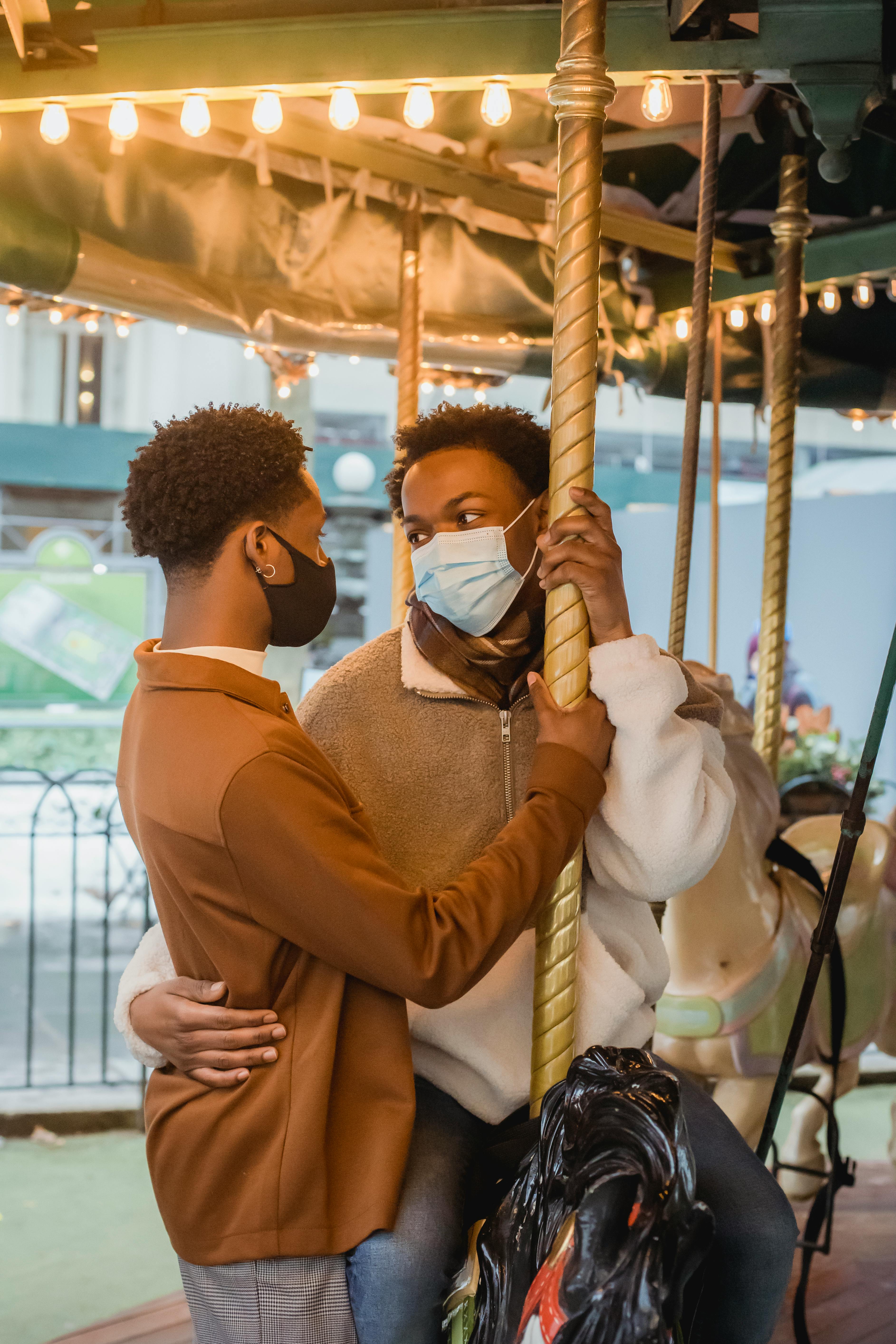 romantic young black gay couple hugging on carousel