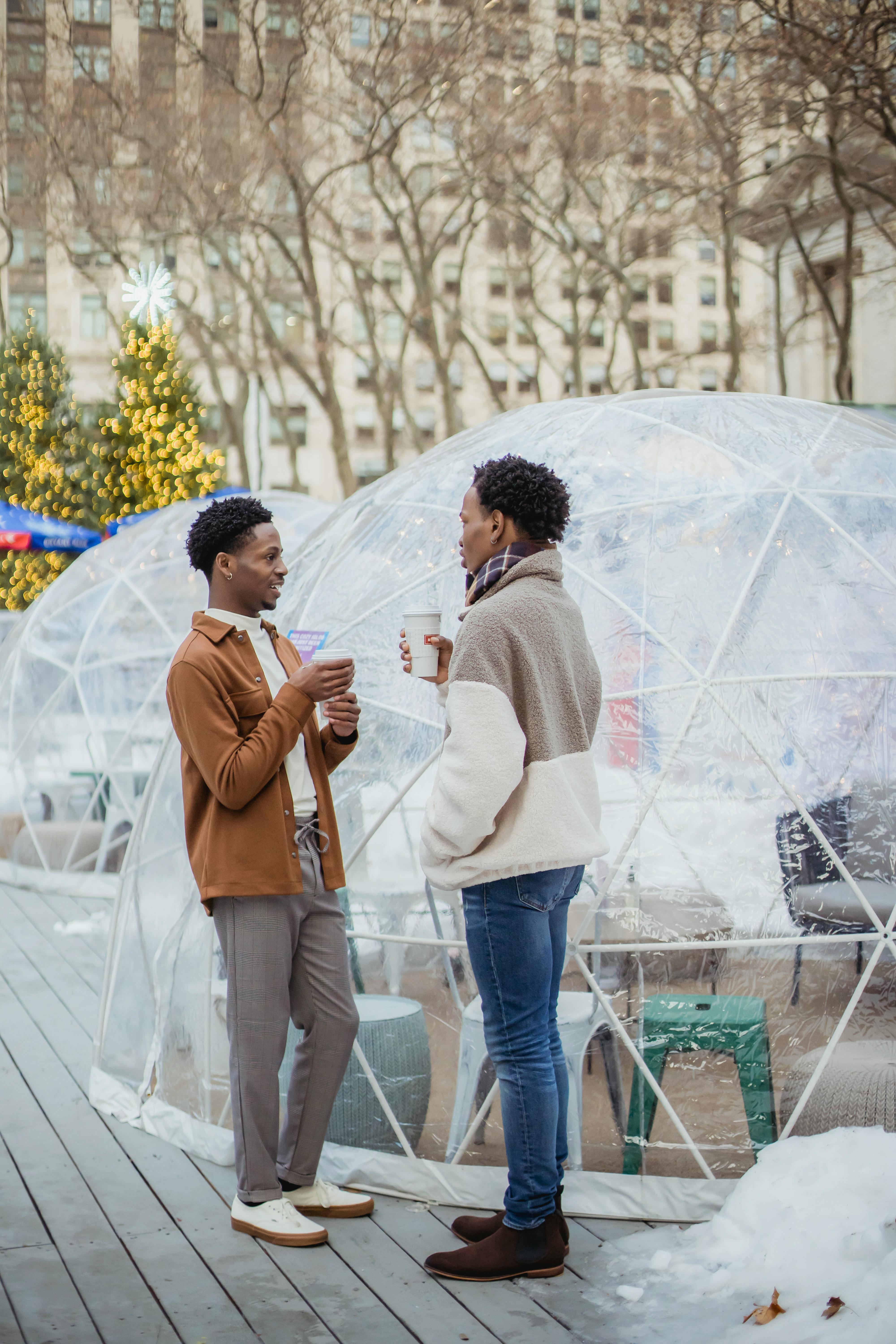 content young black gays chatting on street and drinking hot beverages