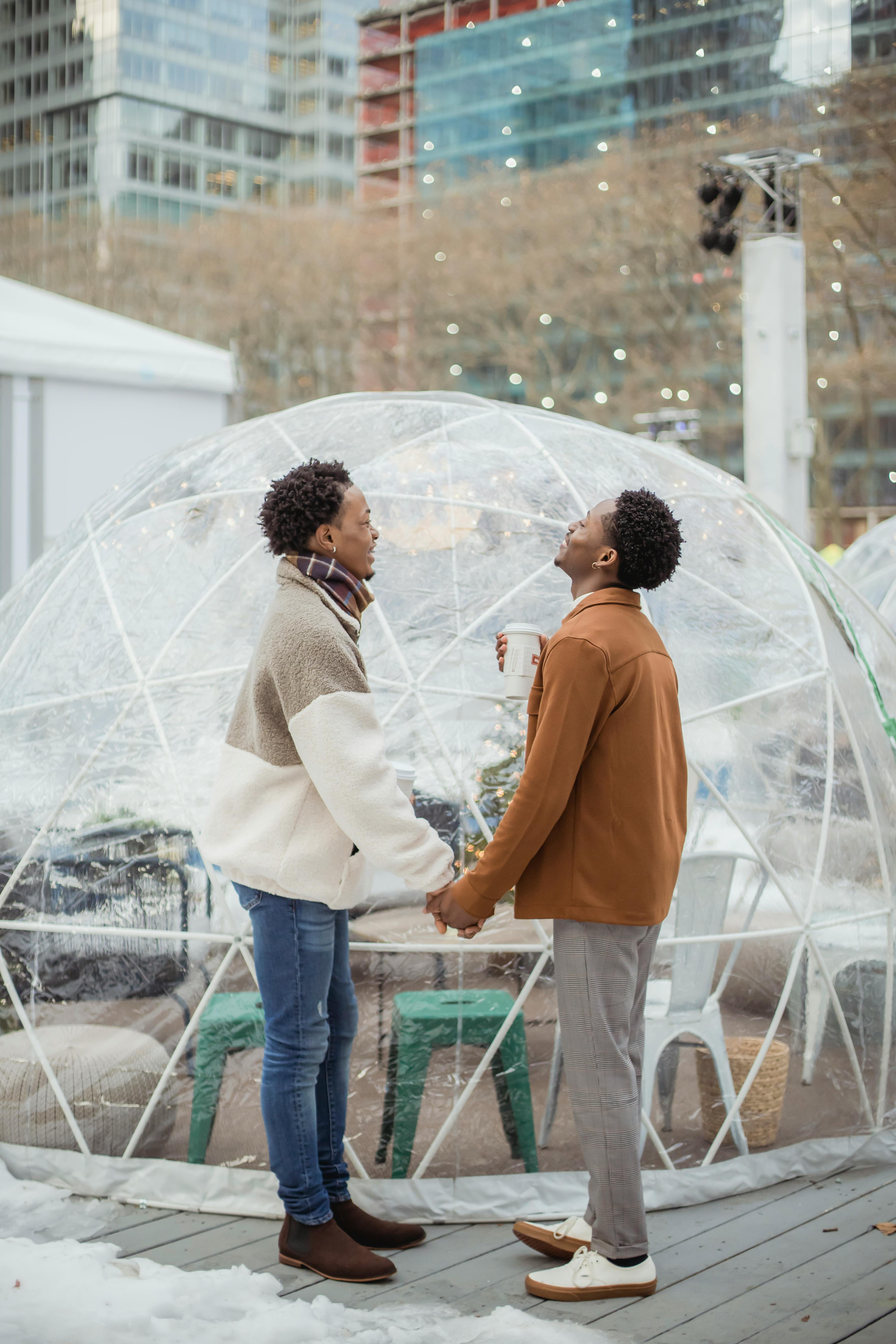 joyful young gays holding hands while spending time together in city