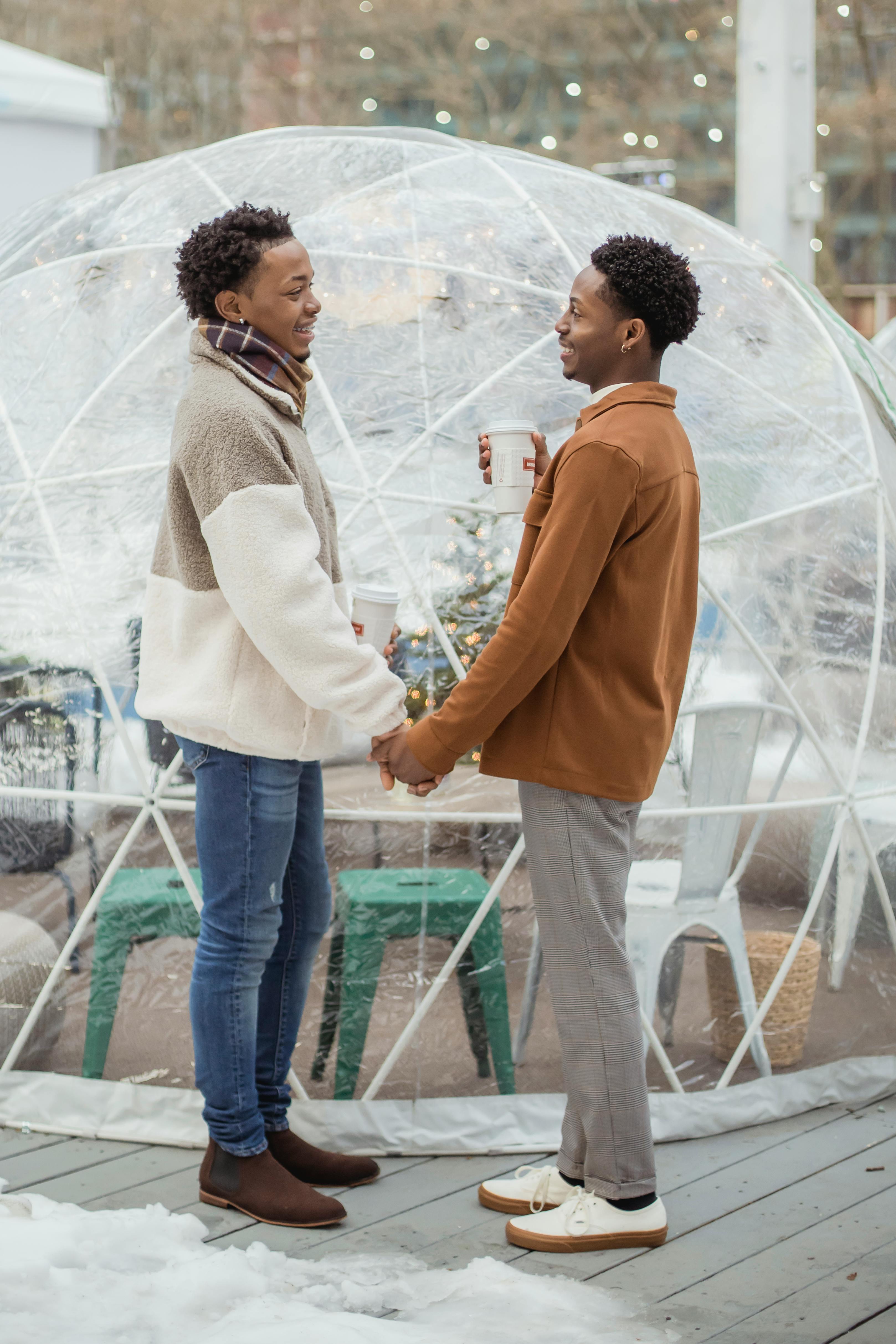 loving black gay couple holding hands and drinking hot coffee on city street