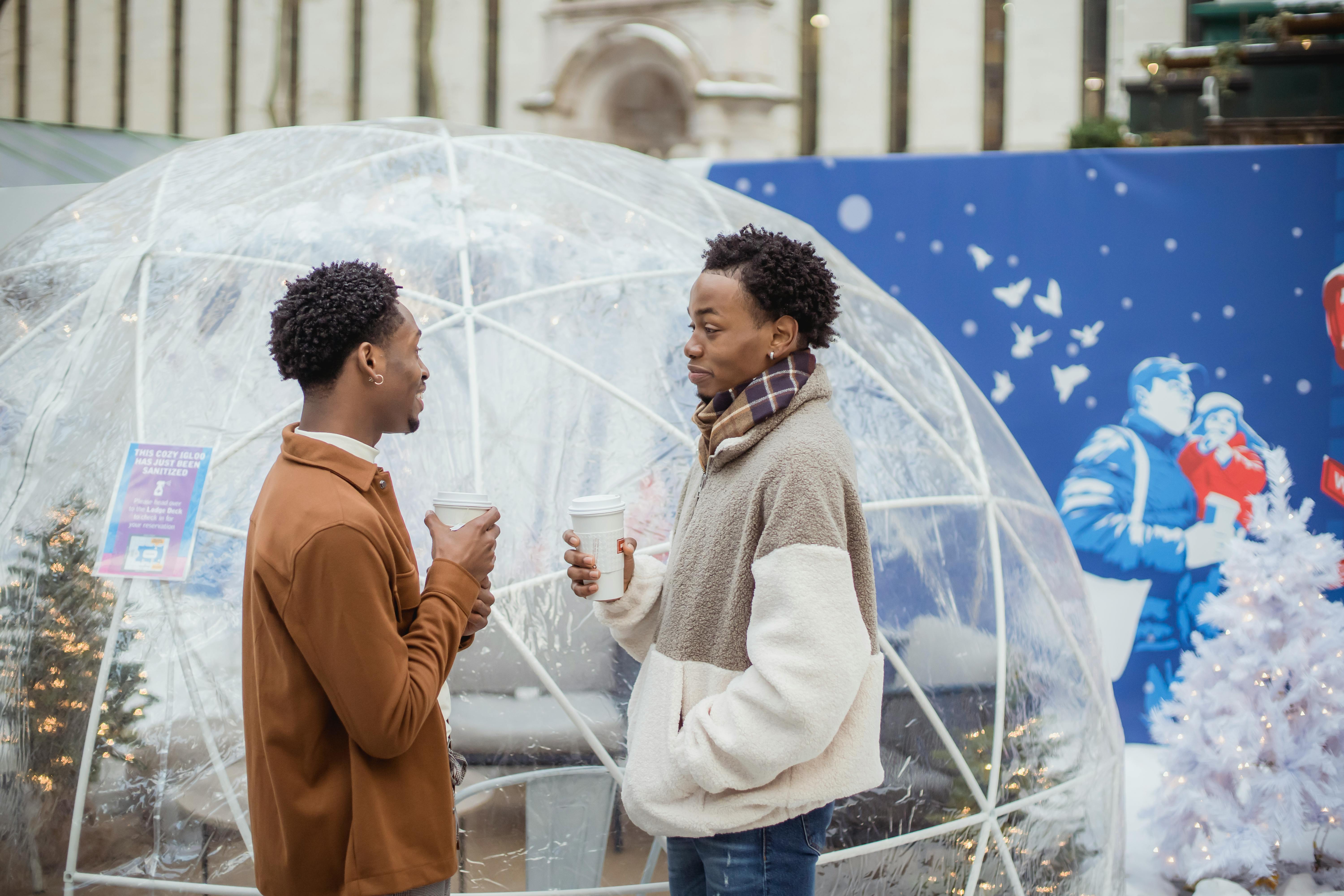 black boyfriends communicating on street with cups of coffee