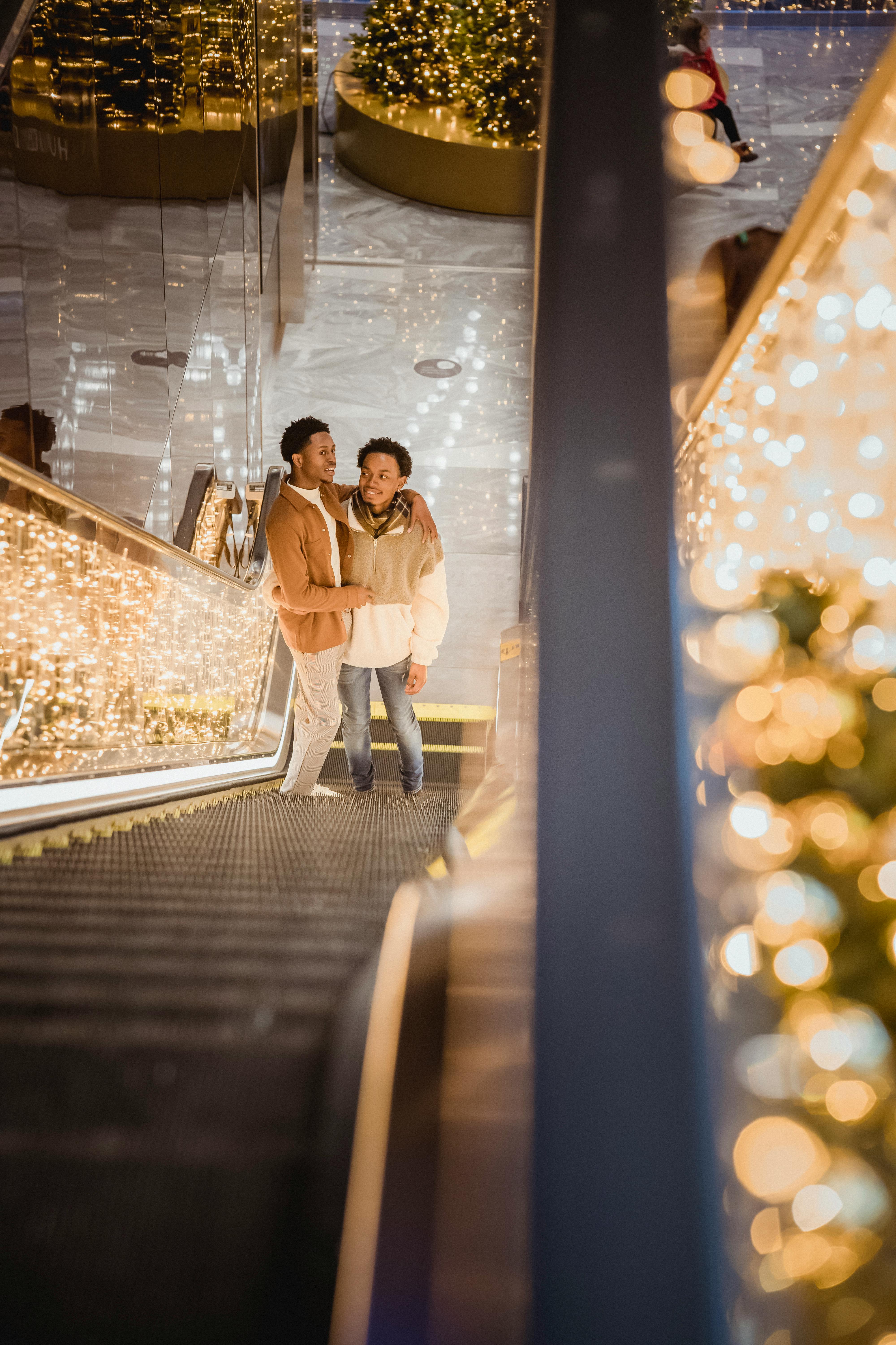 embracing black homosexual couple standing on illuminated escalator