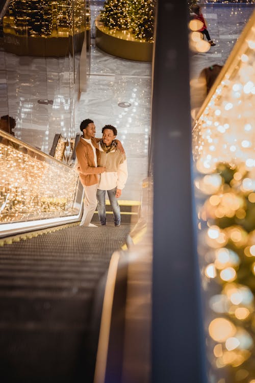 Free Embracing black homosexual couple standing on illuminated escalator Stock Photo