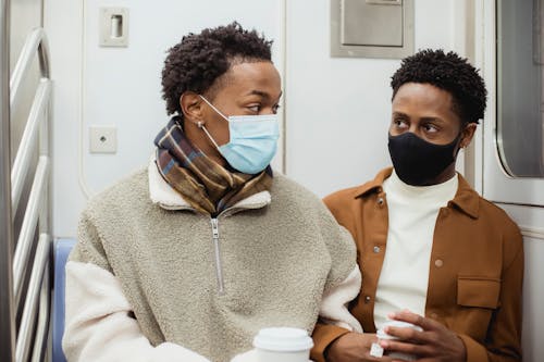 Black homosexual partners sitting in underground carriage