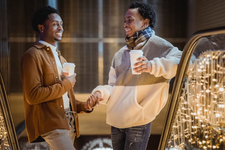 African American Men Holding Hands On Escalator