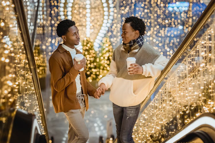 African American Gay Couple Holding Hands While Going Towards By Escalator